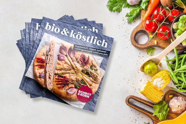 KI generiert: Das Bild zeigt mehrere Exemplare eines Magazins mit dem Titel "bio & köstlich", das sich auf vegetarische, vegane und saisonale Rezepte konzentriert. Daneben ist eine Auswahl an frischem Gemüse und Kräutern zu sehen.